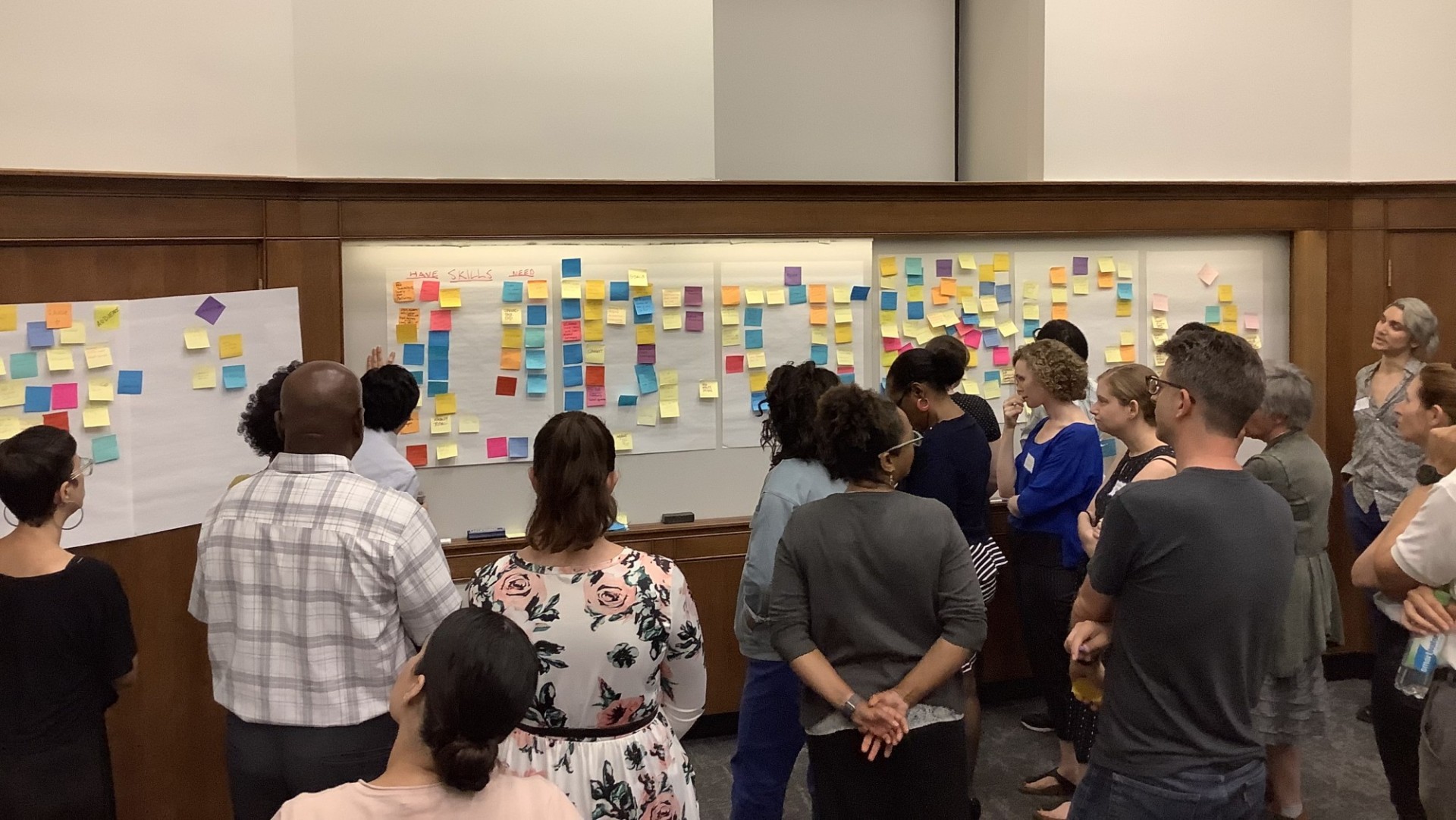 Group of people looking at whiteboards covered in sticky notes